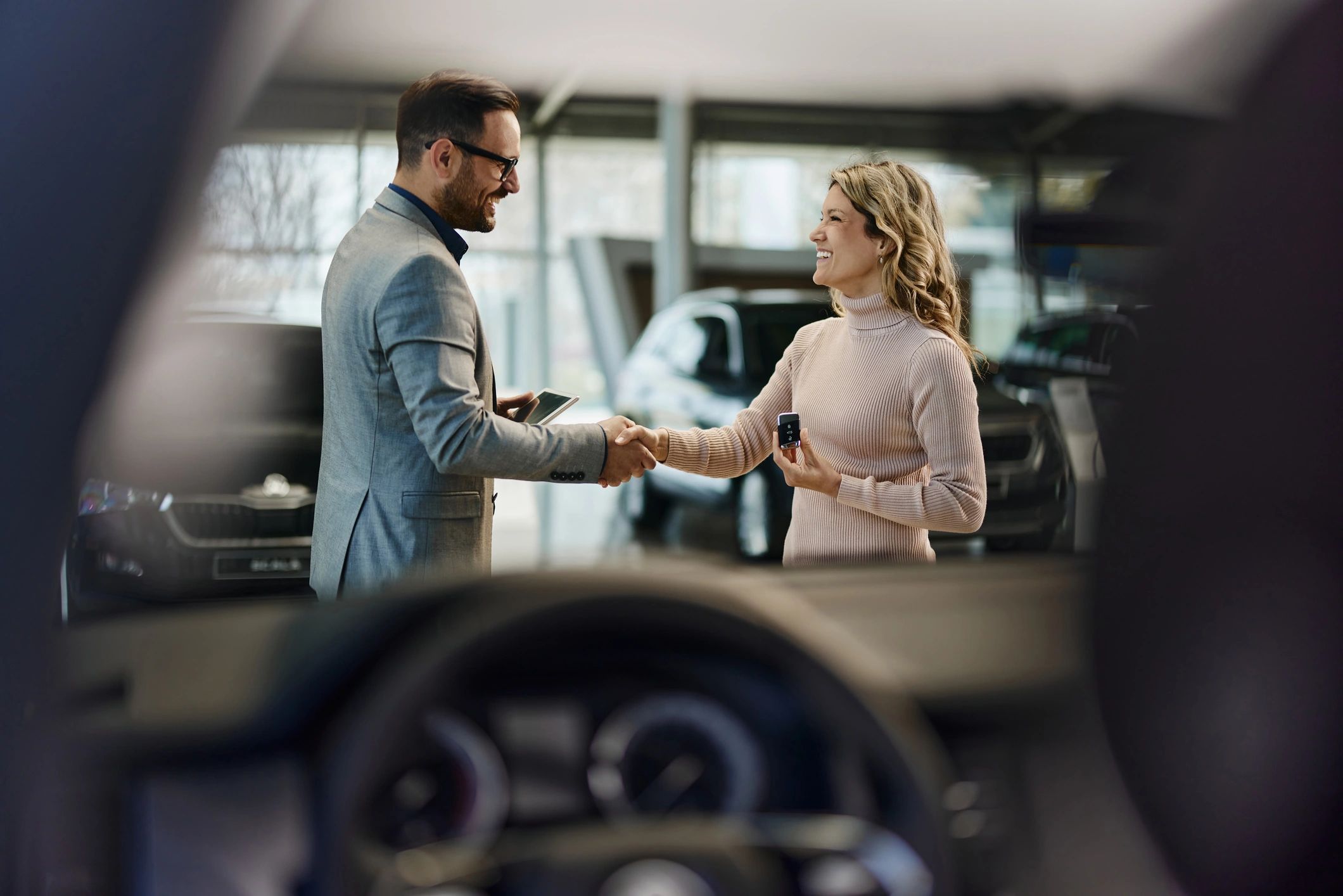 Customer receiving car keys in a dealership showroom