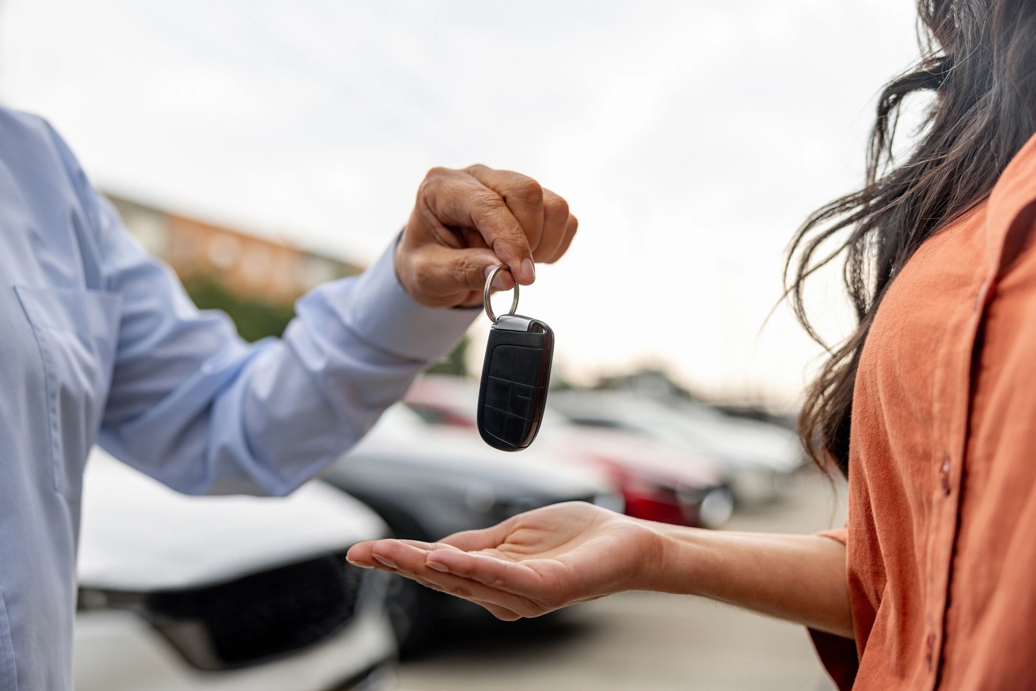 Salesperson handing car keys to a customer at a dealership