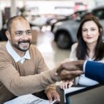 Customer shaking hands with car salesman buying a car